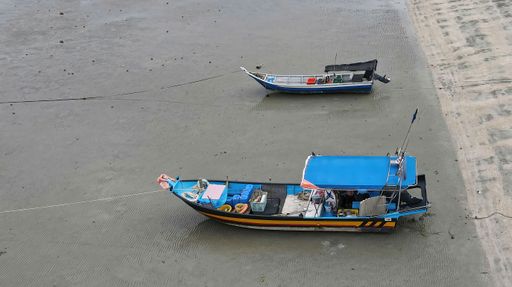 An aerial view of traditional fishing boats moored on an empty sandy beach