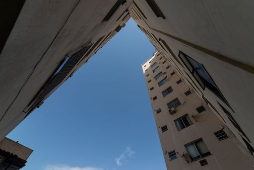 A low-angle of exterior view of a tall, multi-story building with a blue sky in the background