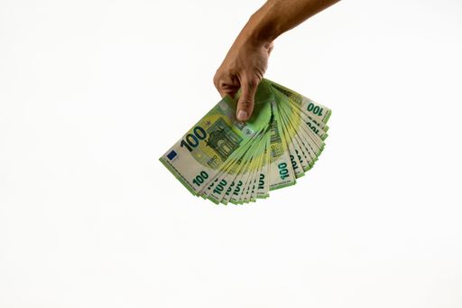 A male hand holding a bunch of green q00 Euro bills on a white background