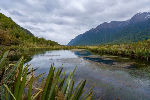 A landscape view with Mirror Lakes on a gloomy day, snowy mountains and cloudy sky background