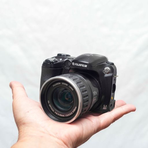 A closeup shot of a Fujifilm Finepix s5200 compact camera in the palm of a person