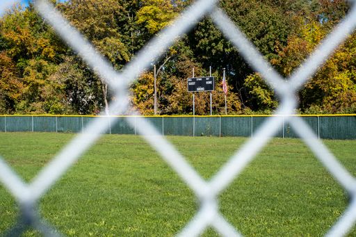 A natural view of a baseball field with blurry metal fence foreground