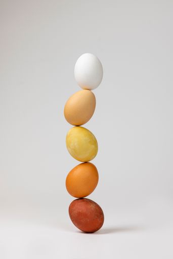 A vertical shot of Easter eggs stacked on top of one another on a white background