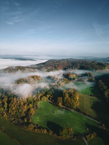A vertical drone shot of fog over a small town and hills in Germany