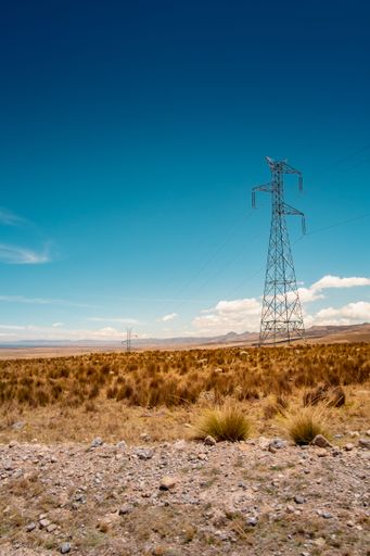 A vertical shot of a high voltage tower in the valley of the Peruvian Andes