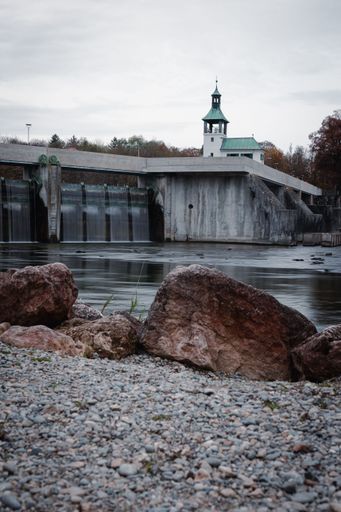 A vertical shot of the Hochablass seen from the rocky shore under the cloudy sky in Augsburg, Germany