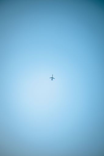 A vertical low angle shot of an airplane flying in a clear blue sky
