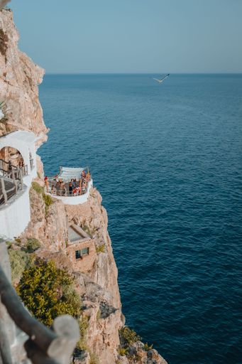 A vertical shot of a party on the side of a cliff over the water in Mallorca, Spain