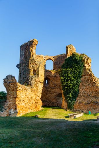 A vertical shot of the ruins of an old building under a blue sky.