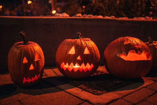 The carved Halloween pumpkins on the ground at night.