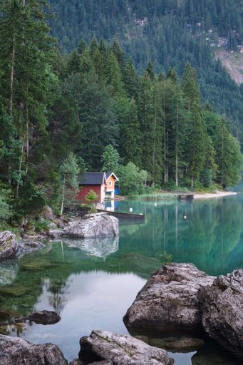 A vertical shot of a house in front of lake Eibsee with forest in the background, Bavaria, Germany