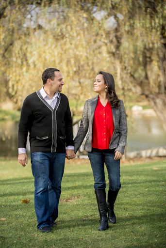 A vertical shot of a couple holding hands while walking on a grassy field