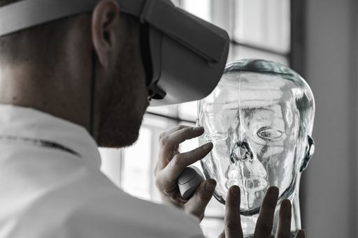 A young doctor wearing VR goggles examining a transparent mannequin in a virtual reality simulation for practice - the future of healthcare concept