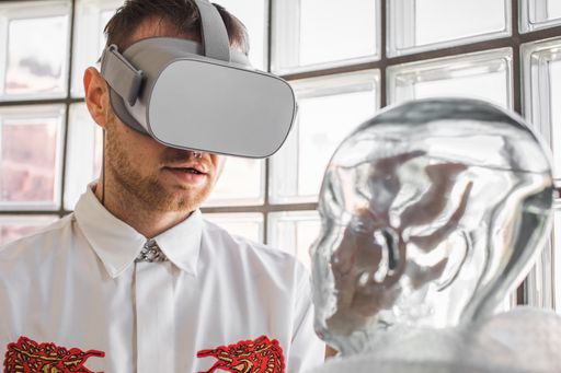 A person wearing virtual reality goggles holding a transparent mannequin