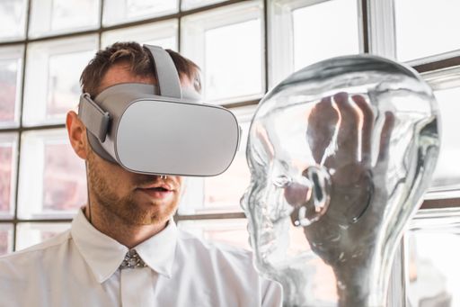 A young doctor wearing VR goggles examining a transparent mannequin in a virtual reality simulation for practice - the future of healthcare concept