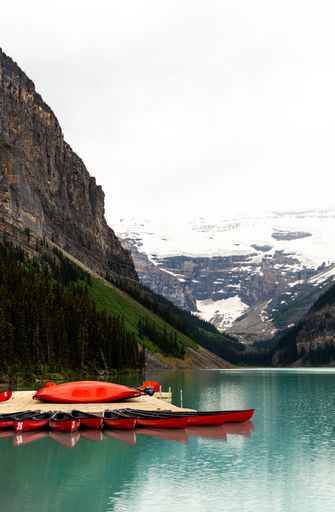 A row of empty red kayaks lined up on the edge of Lake Louise in Banff National Park