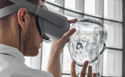 A young doctor wearing VR goggles examining a transparent mannequin in a virtual reality simulation for practice - the future of healthcare concept