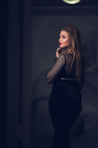 A vertical shot of a pretty model in a black outfit and red lipstick  posing