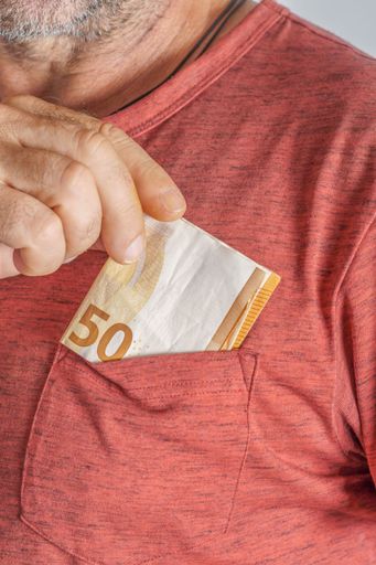 close-up of man putting euro banknotes in his red T-shirt pocket