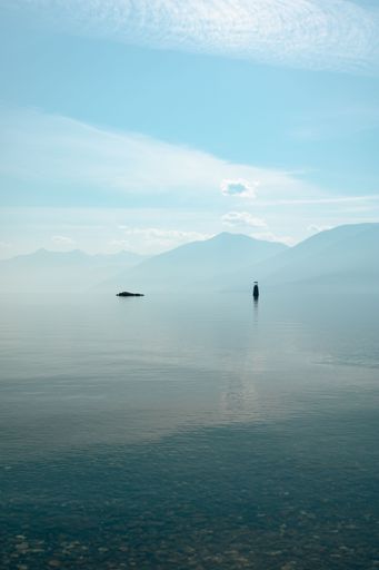 A vertical shot of a Kootenay Lake with crystal clear water and mountains in the background, BC Canada