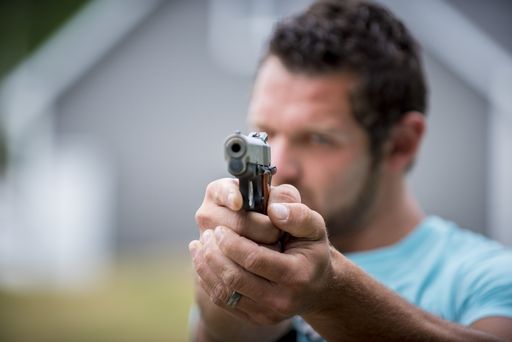 A male holding a pistol up towards the camera