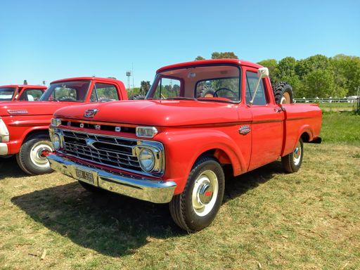 Old red 1968 Ford F 100 pickup truck in the countryside. Nature, grass, trees. Autoclasica 2022 classic car show