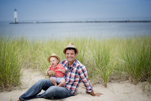A shallow focus shot of a father and a son on a sandy surface near the beach