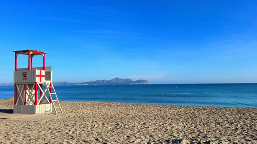 A lifeguard station on a sandy beach under a blue sky.
