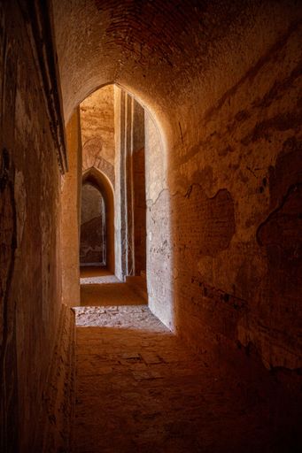 Sunlight shines into an arched brick corridor, in one of the many temples of Bagan, Myanmar.