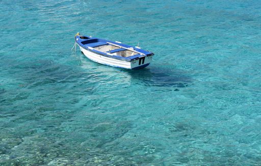 An aerial view of a small boat in a shallow blue sea
