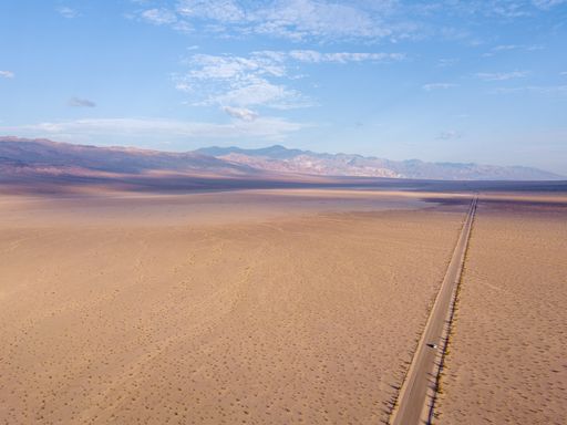 An aerial shot of a huge salt lake with an endless road in the Death Valley