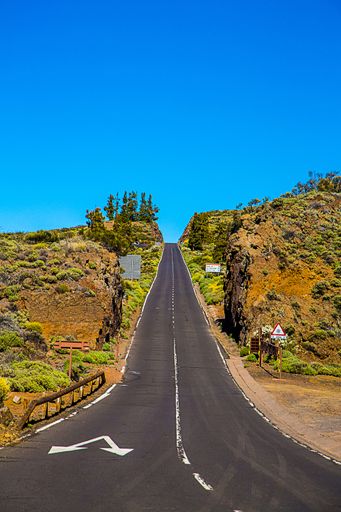 A vertical shot of an empty road near the Teide volcano in Spain on a blue sky background