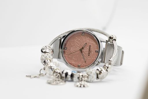 A close-up shot of a silver Pandora hand watch and a bracelet isolated on a white background