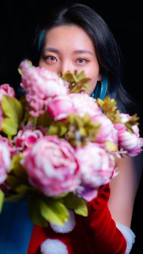 The vertical portrait of a girl with blue-colored hair hiding behind a bucket of roses