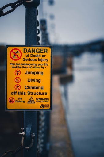A vertical closeup shot of a danger warning sign near the water in Folkstone, UK
