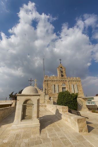 A vertical low angle shot of a concrete church under the cloudy sky
