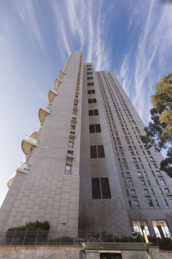 A vertical low angle shot of a tower block under the cloudy sky