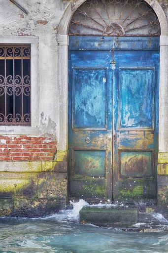 A vertical shot of an old blue vintage door near a canal during daytime