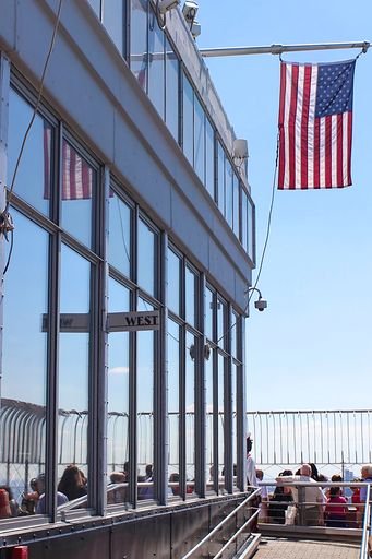 A vertical shot of the Empire State Building viewpoint with a flag of The United States. New York.