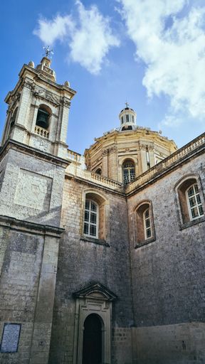 A vertical low angle of the St Pauls Cathedral in Mdina Malta with a cloudscape in the background