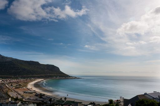 A drone shot of Fish Hoek beach with calm sea and mountain in the background in Cape Town, south Africa