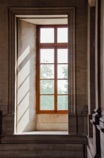A vertical shot of light shining through the wooden window of stone building