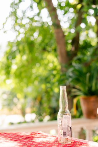 A vertical shot of a beer bottle on the table in the yard with trees in the background