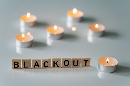 A closeup shot of a wooden black out sign near burning tea candles on a gray surface