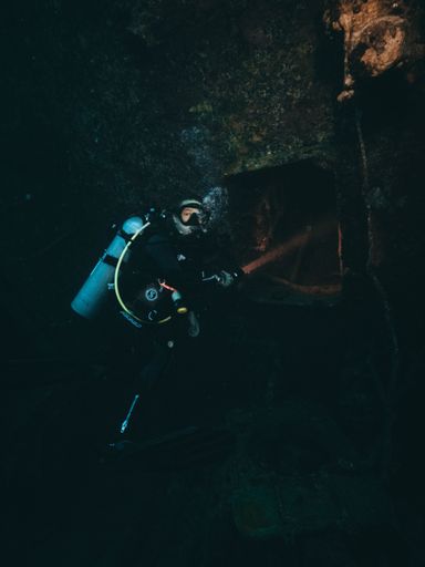 A scuba diver exploring the mysterious ship wrecks, in a vertical shot