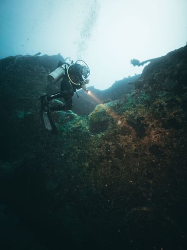 A scuba diver exploring the mysterious ship wrecks, in a vertical shot