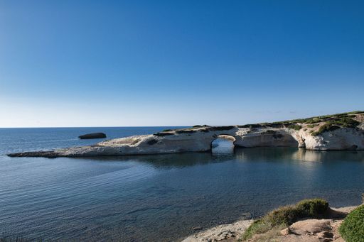 A majestic shot of Sarchittu beach and the Limestone rock with arch in the Central Western part of Sardinia