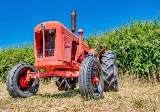 A red vintage tractor in the farmlands on a sunny day