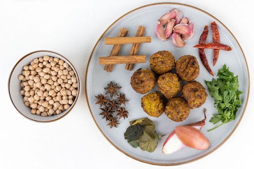 A top view of a round plate of falafels and the ingredients for cooking the dish