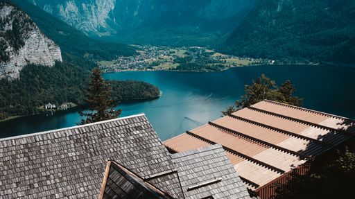 A drone shot of roofs of houses on the coast of a small lake surrounded by hills in Hallstatt, Austria